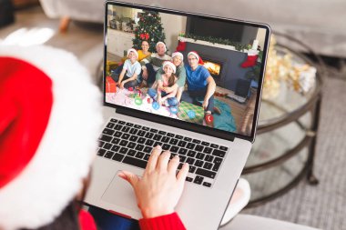 Kafkasyalı bir kadın Kafkasyalı bir aileyle Noel 'de görüntülü görüşme yapıyor. İletişim teknolojisi ve noel, dijital kompozit görüntü.