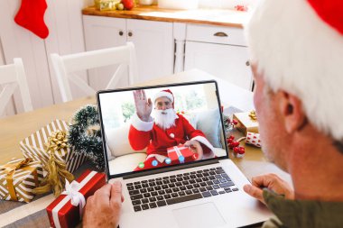 Kafkasyalı son sınıf öğrencisi, Noel Baba kostümü giyen Kafkasyalı bir adamla Noel 'de görüntülü görüşme yapıyor. İletişim teknolojisi ve noel, dijital kompozit görüntü.