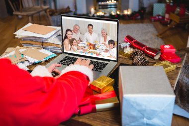 Kafkasyalı kıdemli bir adam Kafkasyalı bir aileyle Noel 'de görüntülü görüşme yapıyor. İletişim teknolojisi ve noel, dijital kompozit görüntü.
