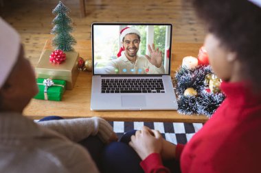 Afrika kökenli Amerikalı bir çift, melez bir adamla Noel 'de görüntülü görüşme yapıyor. İletişim teknolojisi ve noel, dijital kompozit görüntü.