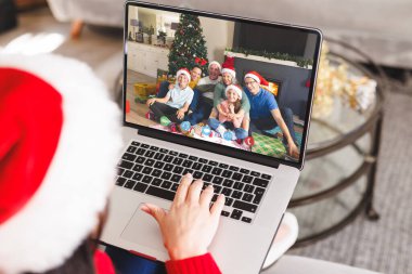 Kafkasyalı bir kadın Kafkasyalı bir aileyle Noel 'de görüntülü görüşme yapıyor. İletişim teknolojisi ve noel, dijital kompozit görüntü.