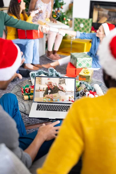 シニア白人男性とクリスマスビデオ通話を持っている友人の多様なグループ 通信技術とクリスマス デジタル複合画像 — ストック写真