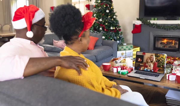 アフリカ系アメリカ人のシニア夫婦が白人女性と娘とクリスマスビデオ通話をしている 通信技術とクリスマス デジタル複合画像 — ストック写真