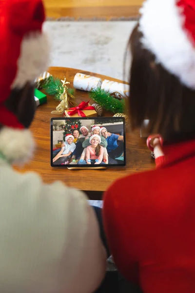 Diverse couple having christmas video call with caucasian family. Communication technology and christmas, digital composite image.