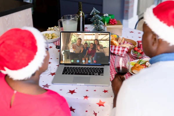 Senior african american couple having christmas video call with biracial family. Communication technology and christmas, digital composite image.