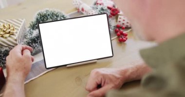 Kafkasyalı adam noel süslemeleri ile fotokopi alanı ile tablet video görüşmesi yapıyor. Noel, şenlik ve iletişim teknolojisi.