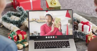 Noel Baba şapkalı çeşitli çiftler Afro-Amerikan bir adamla dizüstü bilgisayar görüşmesi yapıyorlar. Noel, kutlama, dijital kompozit video.