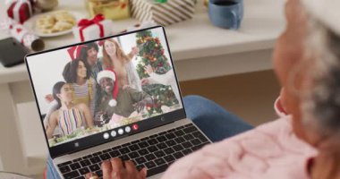 Kıdemli Afro-Amerikan kadın çeşitli insanlarla yılbaşı videosu çekiyor. İletişim teknolojisi ve noel, dijital kompozit video.