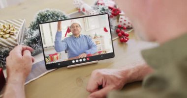 Kafkasyalı, noel süslemeleri olan, melez bir adamla tablet video görüşmesi yapan bir adam. Noel, kutlama, dijital kompozit video.