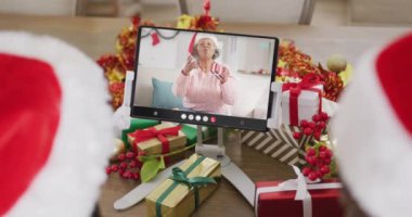 Noel Baba şapkalı beyaz bir çift mutlu Afro-Amerikan bir kadınla tablet görüntülü görüşme yapıyorlar. Noel, şenlik ve iletişim teknolojisi.