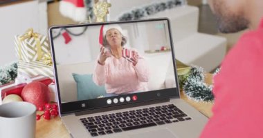 Afrikalı Amerikalı bir adam Noel süsleriyle Afro-Amerikan bir kadınla görüntülü görüşme yapıyor. Noel, gelenek ve kutlama konsepti, dijital kompozit video.