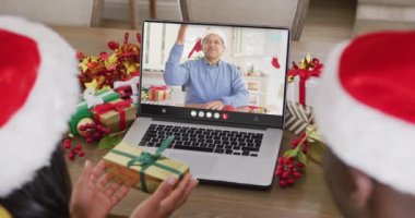 Noel Baba şapkalı çeşitli çiftler, çift ırklı bir adamla dizüstü bilgisayar görüşmesi yapıyorlar. Noel, kutlama, dijital kompozit video.