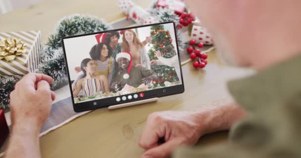 幸せな多様な友人とタブレットビデオコールを持つクリスマスの装飾を持つ白人男性 クリスマス お祭り 通信技術 — ストック動画