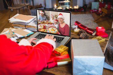 Kafkasyalı kıdemli bir adam Kafkasyalı bir aileyle Noel 'de görüntülü görüşme yapıyor. İletişim teknolojisi ve noel, dijital kompozit görüntü.