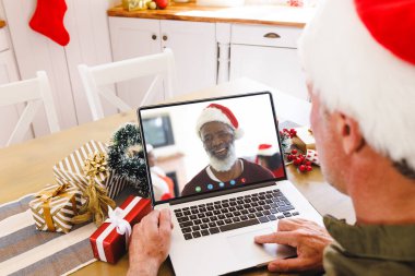 Kıdemli Kafkasyalı adam, kıdemli Afro-Amerikan bir adamla Noel 'de görüntülü görüşme yapıyor. İletişim teknolojisi ve noel, dijital kompozit görüntü.