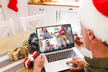 Kafkasyalı kıdemli bir adam çeşitli insanlarla yılbaşı videosu çekiyor. İletişim teknolojisi ve noel, dijital kompozit görüntü.