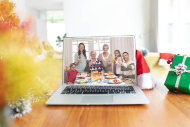 Kafkasyalı bir ailenin dizüstü bilgisayarında noel görüntüsü var. İletişim teknolojisi ve noel, dijital kompozit görüntü.