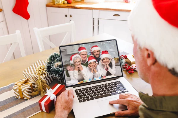 Senior caucasian man having christmas video call with caucasian family. Communication technology and christmas, digital composite image.