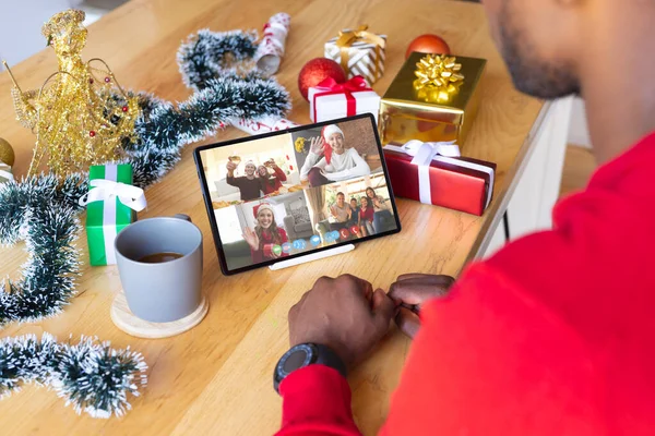 アフリカ系アメリカ人の男性は様々な人とクリスマスビデオ通話をしています 通信技術とクリスマス デジタル複合画像 — ストック写真