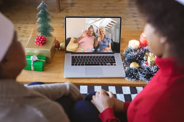 アフリカ系アメリカ人のカップルは シニア白人のカップルとクリスマスビデオ通話をしています 通信技術とクリスマス デジタル複合画像 — ストック写真