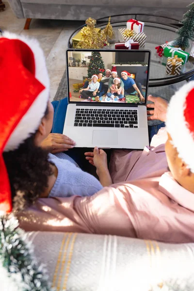 アフリカ系アメリカ人のカップルは白人の家族とクリスマスビデオ通話をしている 通信技術とクリスマス デジタル複合画像 — ストック写真