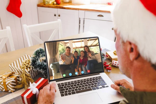 Senior caucasian man having christmas video call with biracial family. Communication technology and christmas, digital composite image.