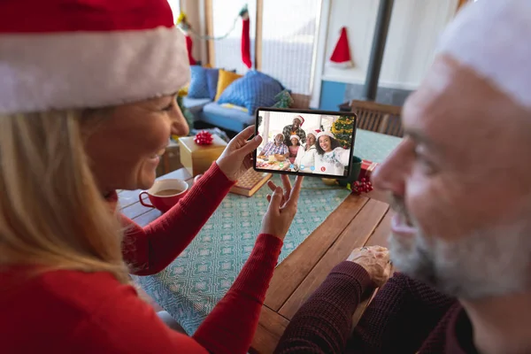 Senior caucasian couple having christmas video call with african american family. Communication technology and christmas, digital composite image.