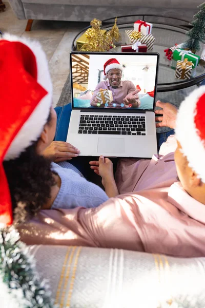 アフリカ系アメリカ人のカップルがアフリカ系アメリカ人の男性とクリスマスビデオ通話をしている 通信技術とクリスマス デジタル複合画像 — ストック写真
