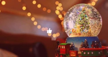 Sosyal medyanın animasyonu kar küresindeki Noel ağacı üzerinde simgeleri parmakla gösteriyor. Noel, kutlama, sosyal medya ve dijital arayüz konsepti dijital olarak oluşturulmuş video.