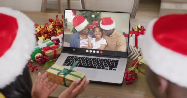 Zróżnicowana Para Kapeluszami Mikołaja Dzwoniąca Przez Laptopa Szczęśliwą Afrykańską Rodziną — Wideo stockowe