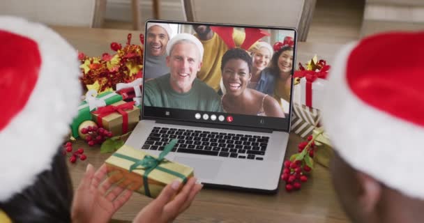 Různorodý Pár Santa Klobouky Notebookem Videohovory Šťastnými Rozmanitými Přáteli Vánoční — Stock video
