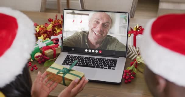 Zróżnicowana Para Kapeluszach Mikołaja Rozmawiająca Przez Laptopa Szczęśliwym Białasem Boże — Wideo stockowe