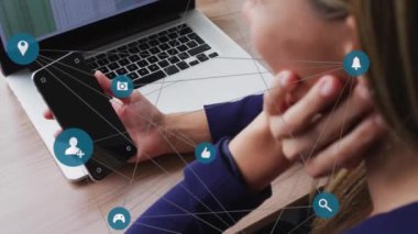 Akıllı telefon ve dizüstü bilgisayar kullanan beyaz kadın üzerindeki medya simgelerinin animasyonu. Küresel iletişim ağı, dijital arayüz ve dijital olarak oluşturulmuş iş veri konsepti.