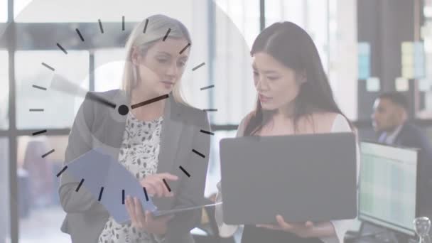 オフィスでノートパソコンの話を使用して2人の多様なビジネス女性以上の時計のアニメーション グローバル通信ネットワーク デジタルインターフェイス ビジネスコンセプトデジタルで生成されたビデオ — ストック動画