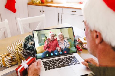 Noel Baba şapkalı beyaz bir adam mutlu Kafkasyalı bir çiftle görüntülü görüşme yapıyor. Noel, kutlama ve dijital kompozit görüntü.