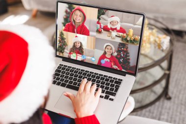 Beyaz kadın, Noel Baba şapkalı mutlu beyaz çocuklarla video görüşmesi yapıyor. Noel, kutlama ve dijital kompozit görüntü.