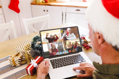 Noel Baba şapkalı beyaz adam mutlu beyaz arkadaşlarıyla görüntülü görüşme yapıyor. Noel, kutlama ve dijital kompozit görüntü.