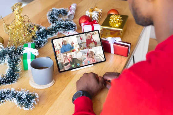 African american man with christmas decorations having video call with happy diverse friends. Christmas, celebration and digital composite image.
