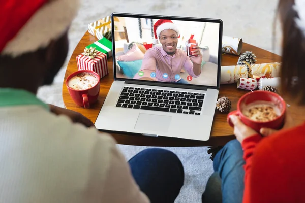 アフリカ系アメリカ人男性とクリスマスビデオ通話を持つ多様なカップル 通信技術とクリスマス デジタル複合画像 — ストック写真