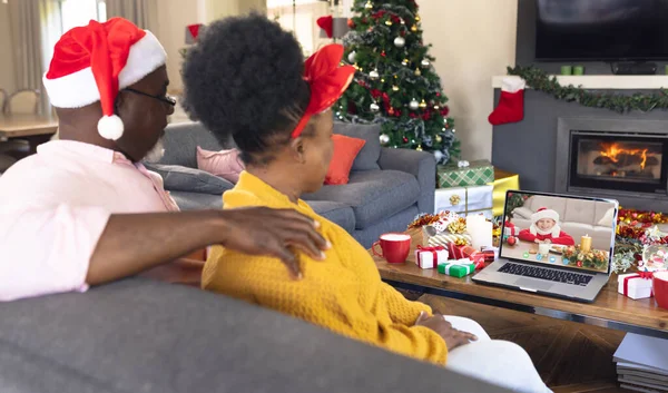 幸せな白人の少年とビデオ通話を持つサンタの帽子を持つアフリカ系アメリカ人のカップル クリスマス お祝いとデジタル複合画像 — ストック写真