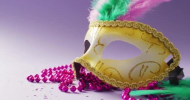 Mor arka planda, tüylü ve pembe boncuklu karnaval maskesi videosu. Karnaval, kostüm, parti malzemeleri, eğlence ve kutlama konsepti..
