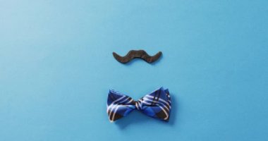 Mavi işaretli papyonlu sahte bıyıklı sahte bir bıyık videosu. Fotokopi alanı ile mavi arka plan. Babalar günü, kostüm, parti malzemeleri, eğlence ve kutlama konsepti..