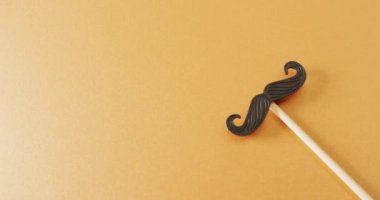 Sarı arkaplandaki sahte bıyıklı fotokopi alanı videosu. Babalar günü, kostüm, parti malzemeleri, eğlence ve kutlama konsepti..