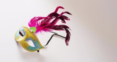 Sarı ve mavi maskeli, beyaz arka planda pembe tüylü, kopyalama alanı olan bir maske. Karnaval, kostüm, parti malzemeleri, eğlence ve kutlama konsepti..