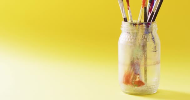 黄色の背景に瓶の中に立っている中古絵筆のコレクションのビデオ アート 創造性 工芸品 趣味の概念 — ストック動画