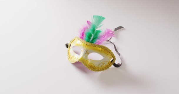 コピースペースと白の背景に緑とピンクの羽を持つマスケードマスクのビデオ カーニバル ドレスアップ パーティーの小道具 楽しさとお祝いのコンセプト — ストック動画