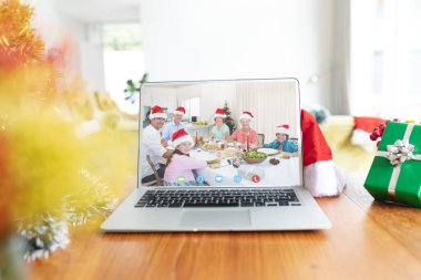 Noel Baba şapkası ve Noel süslemeleri takan mutlu beyaz bir aile dizüstü bilgisayar kullanıyor. Noel, kutlama ve dijital kompozit görüntü.