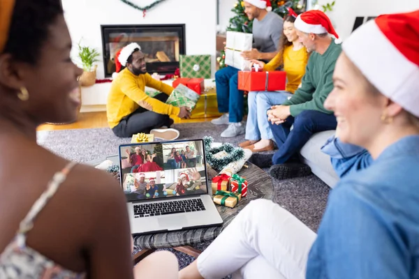 Diverse friends with christmas decorations having video call with happy caucasian friends. Christmas, celebration and digital composite image.