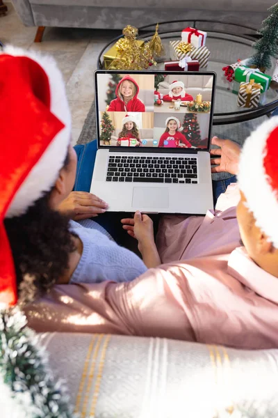 アフリカ系アメリカ人のカップルは 多様な子供たちとクリスマスビデオ通話をしています 通信技術とクリスマス デジタル複合画像 — ストック写真