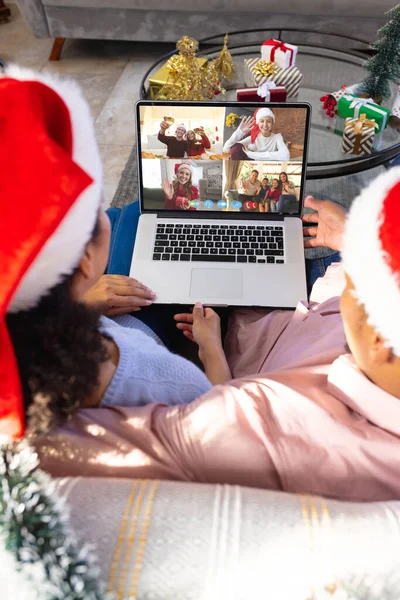 幸せな白人の友人とのビデオ通話を持つサンタの帽子を持つ結婚式のカップル クリスマス お祝いとデジタル複合画像 — ストック写真